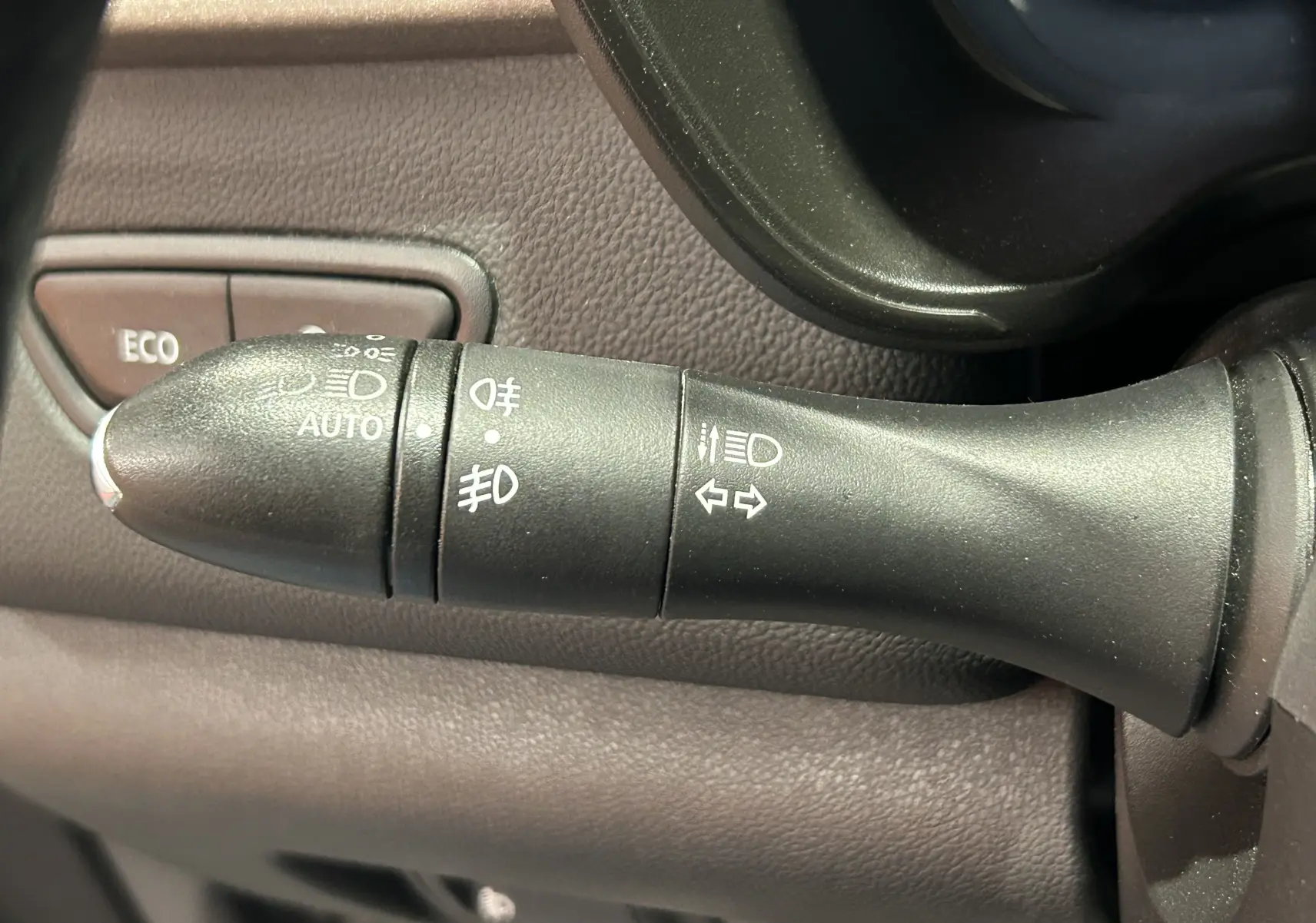 Gros plan sur la commande des feux et clignotants du Renault Kadjar gris, avec bouton ECO en arrière-plan.