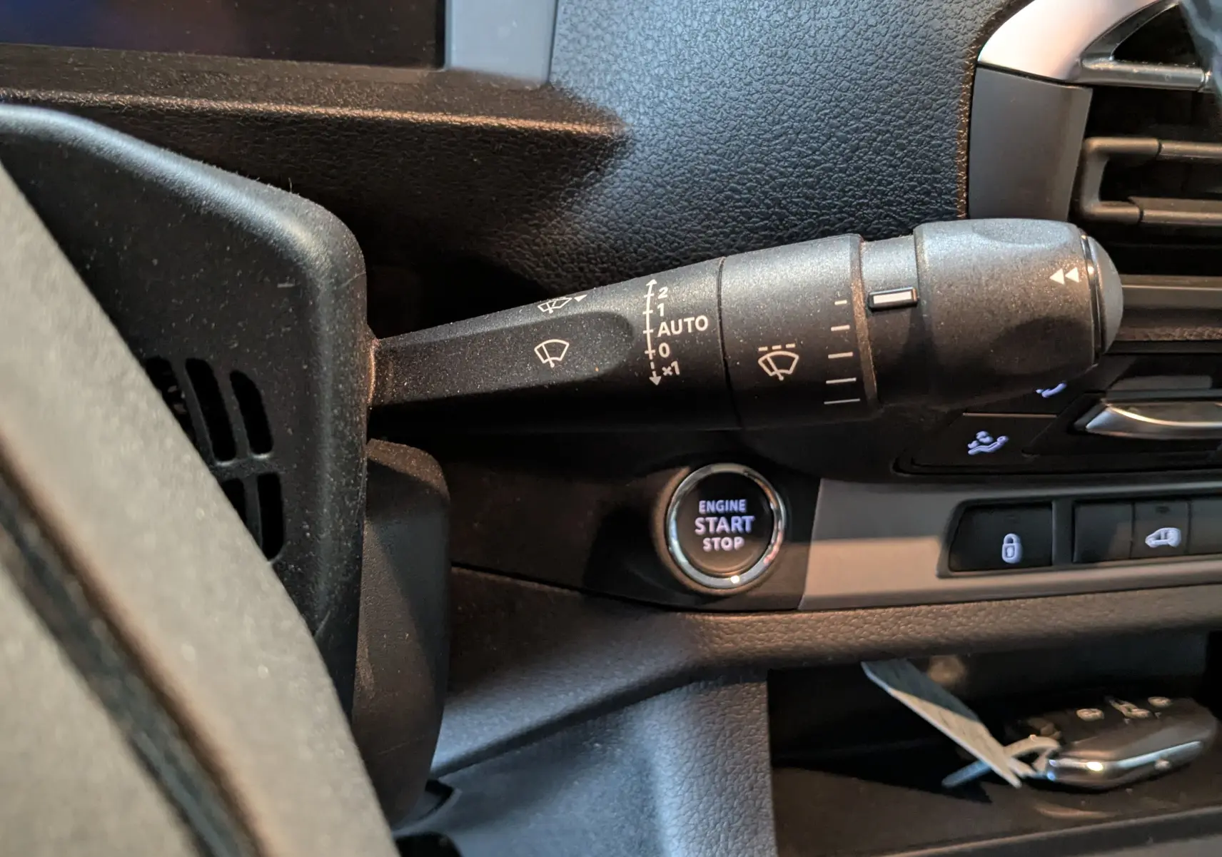 Gros plan sur la commande d’essuie-glace et le bouton start/stop du tableau de bord noir de l’Opel Vivaro Fourgon XL 2024.