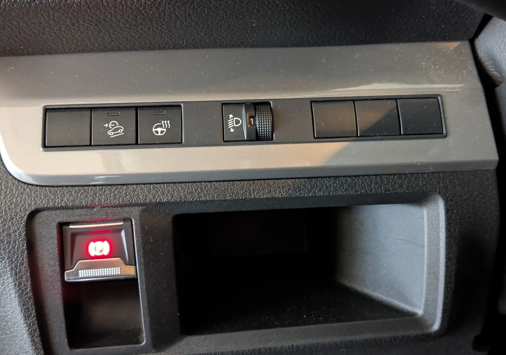 Gros plan sur les commandes du frein à main électronique et réglage des phares dans l’habitacle d’un Opel Vivaro Fourgon blanc.