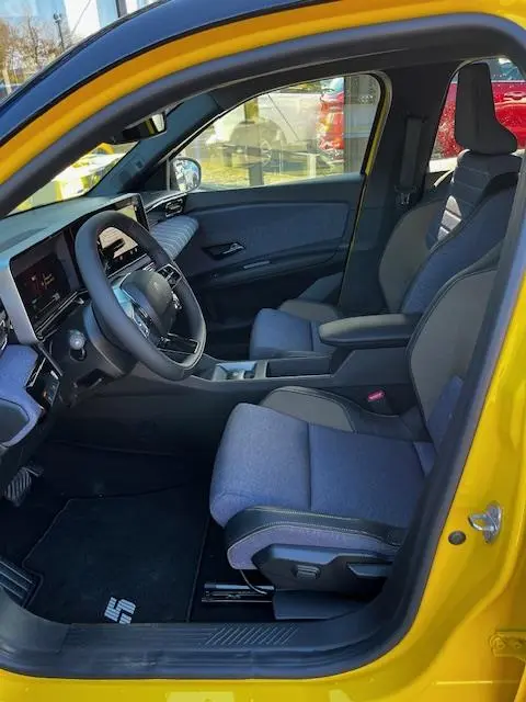 Vue intérieure côté conducteur de la Renault R5 Techno jaune 2024, sièges tissu gris et tableau de bord digital.