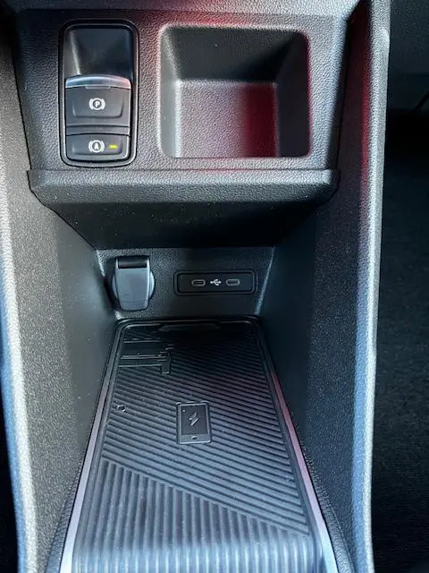 Gros plan sur la console centrale noire de la Renault R5 Techno électrique 2024, avec chargeur sans fil et prises USB.