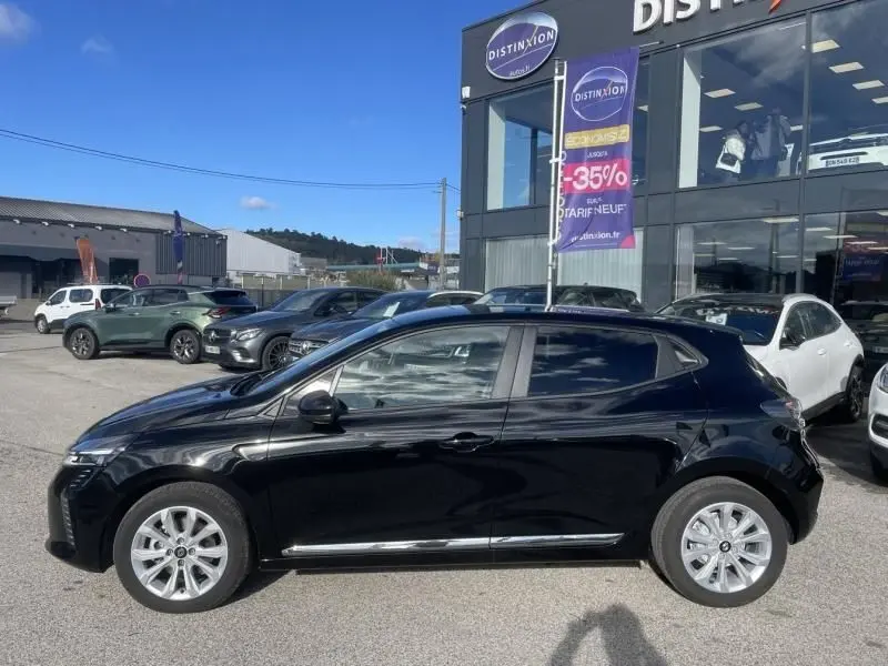 Profil côté gauche de la Renault Clio V noire 1.5 DCI 100 Evolution 2025, garée devant un concessionnaire Distinxion.