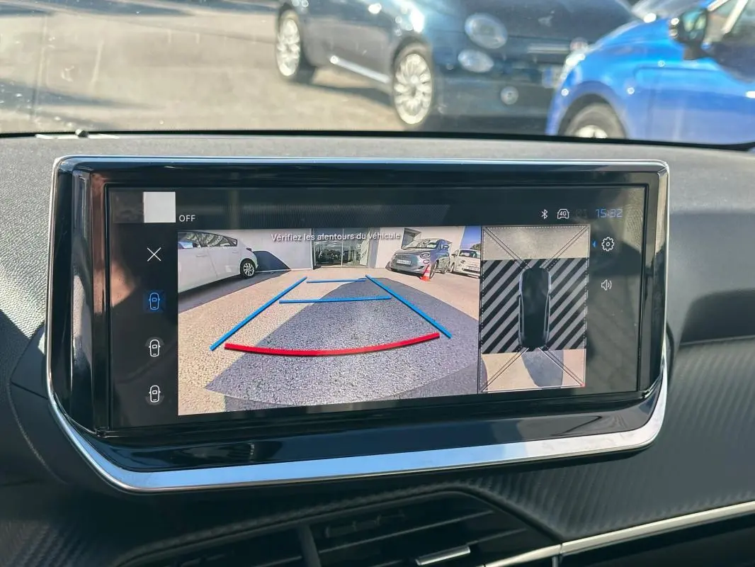 Écran tactile intérieur montrant la caméra de recul et vue 360° du Peugeot 208 gris en stationnement.