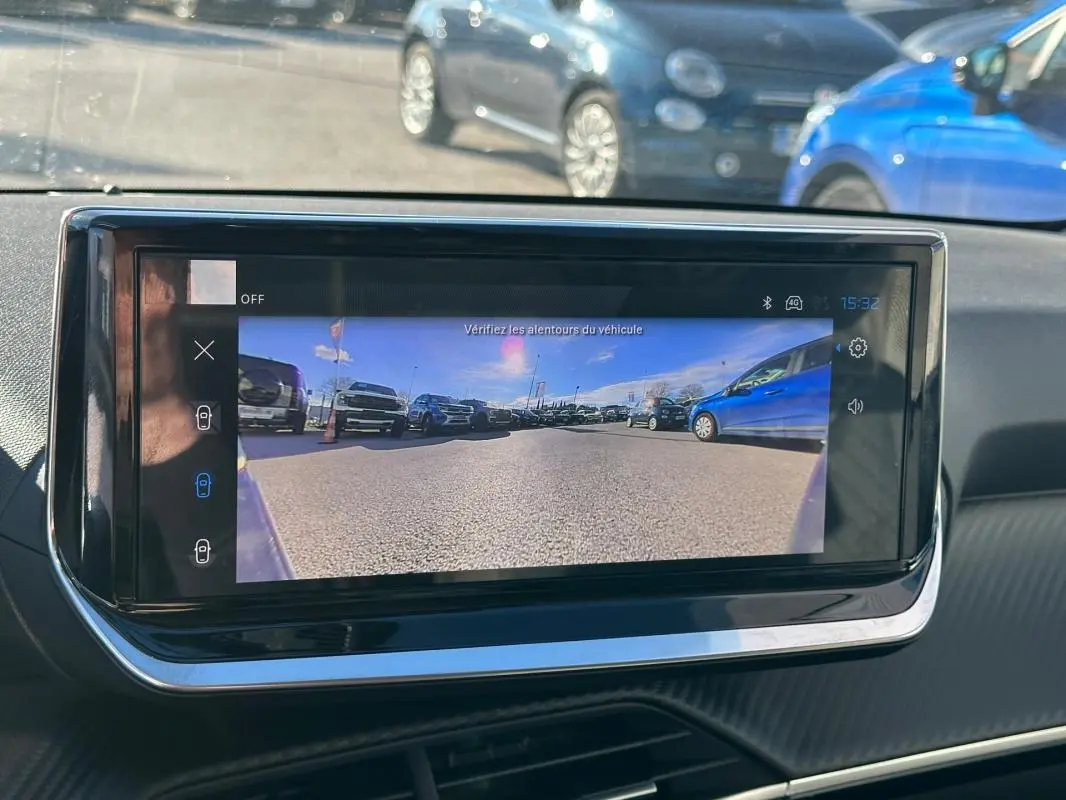 Écran tactile intérieur montrant la caméra de recul d'une Peugeot 208 Hybrid 110 gris, vue depuis le tableau de bord.
