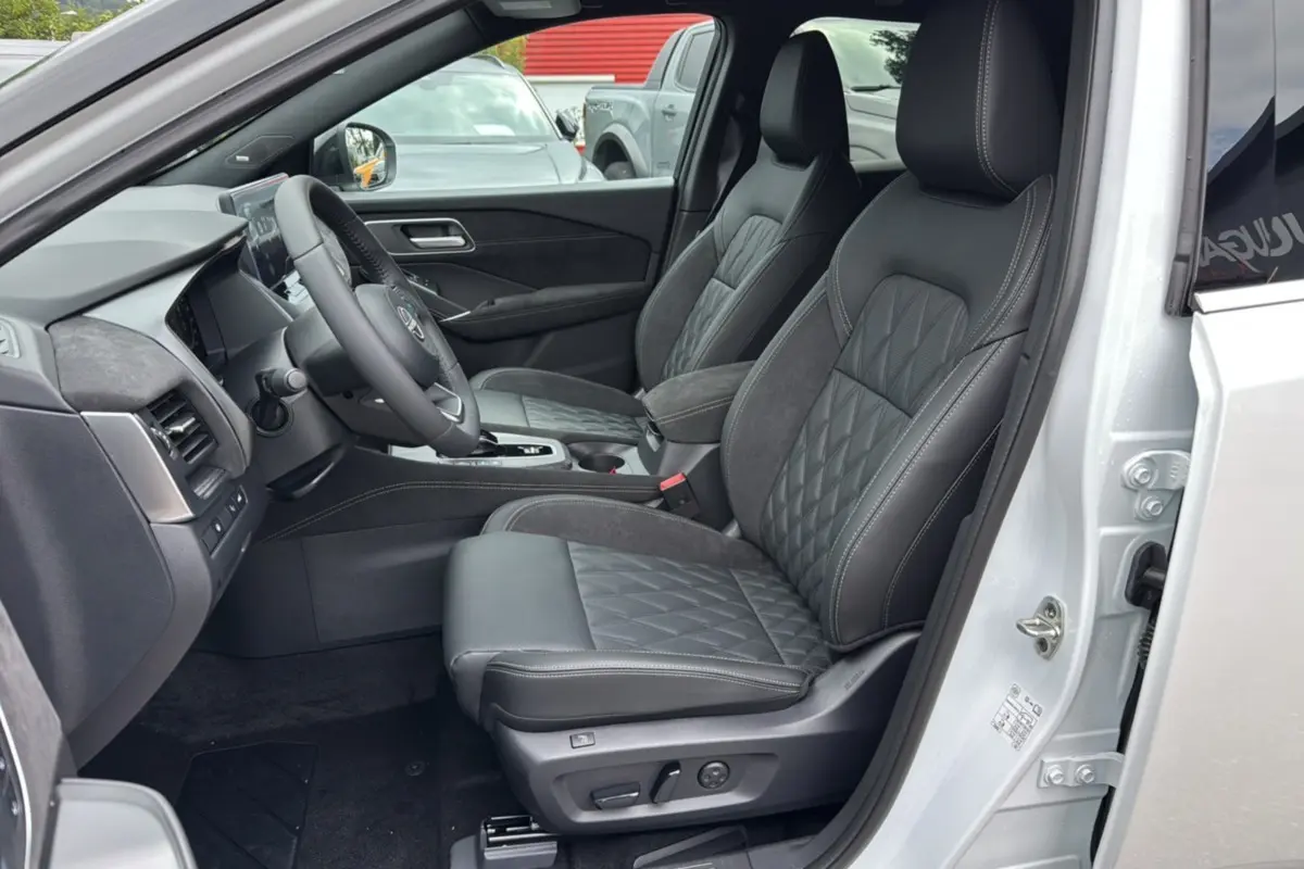 Vue intérieure côté conducteur du Nissan Qashqai blanc lunaire, sièges avant cuir noir matelassé avec surpiqûres grises.