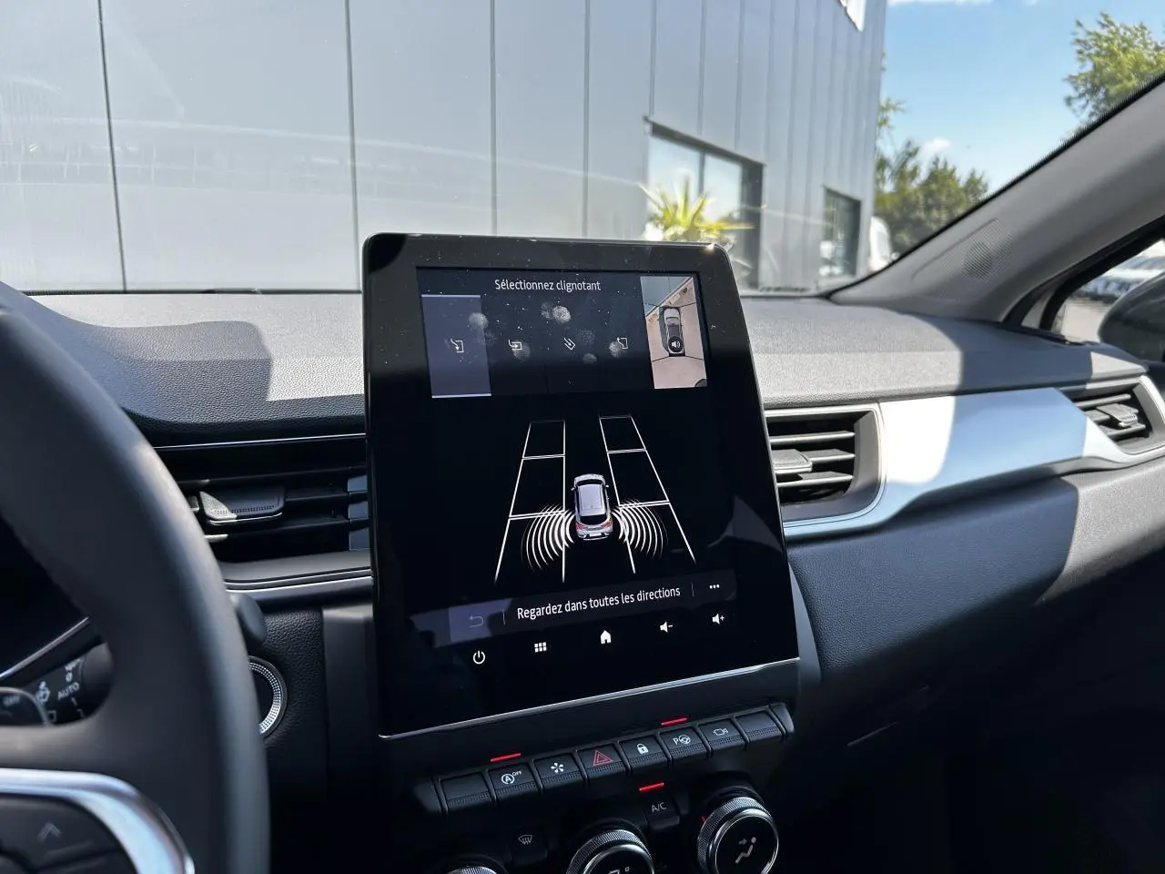 Vue intérieure du tableau de bord du Renault Captur 2024, écran tactile 9,3'' affichant l'assistance au stationnement.