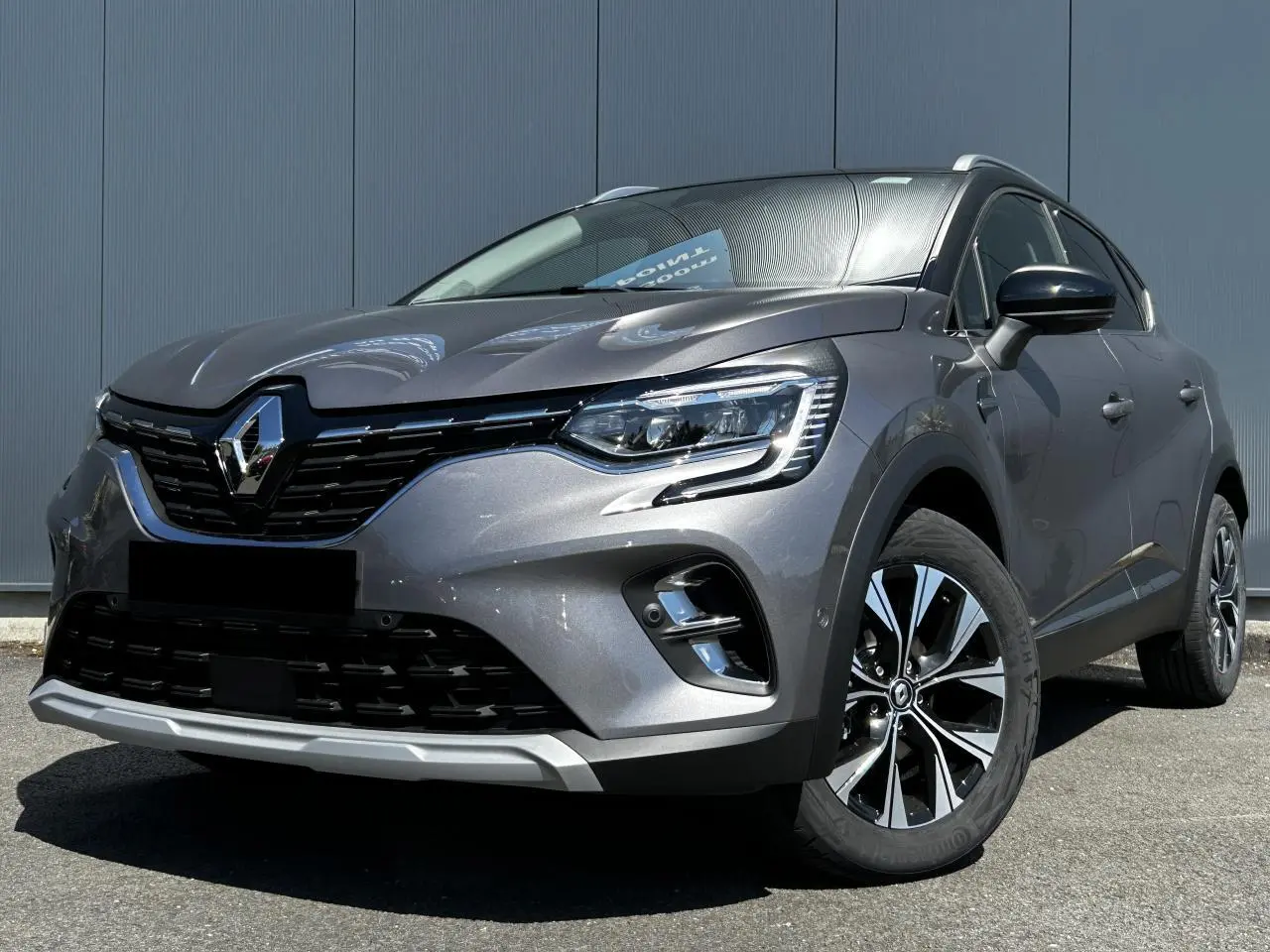 Renault Captur 2024 gris Cassiopée en 3/4 avant droit, avec jantes alliage et toit noir étoilé visible.