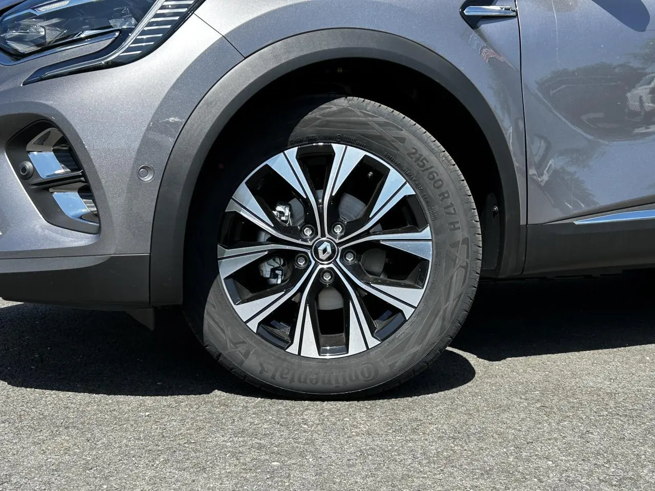 Gros plan sur la roue avant gauche du Renault Captur gris Cassiopée avec jante alliage 17 pouces et partie avant du pare-chocs.
