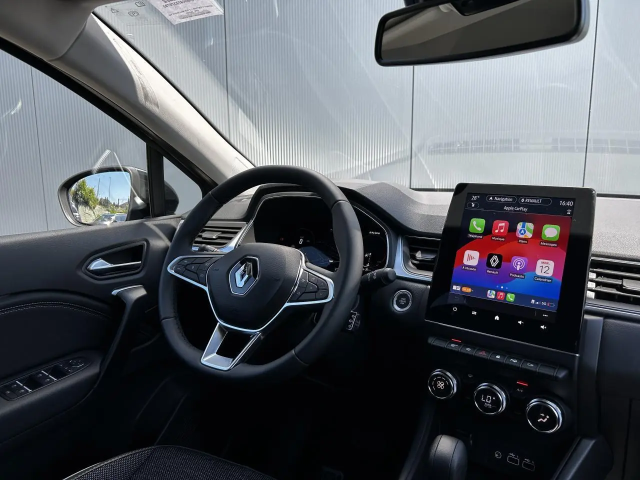 Vue intérieure côté conducteur du Renault Captur 2024 avec écran tactile 9,3'' et volant multifonction noir.