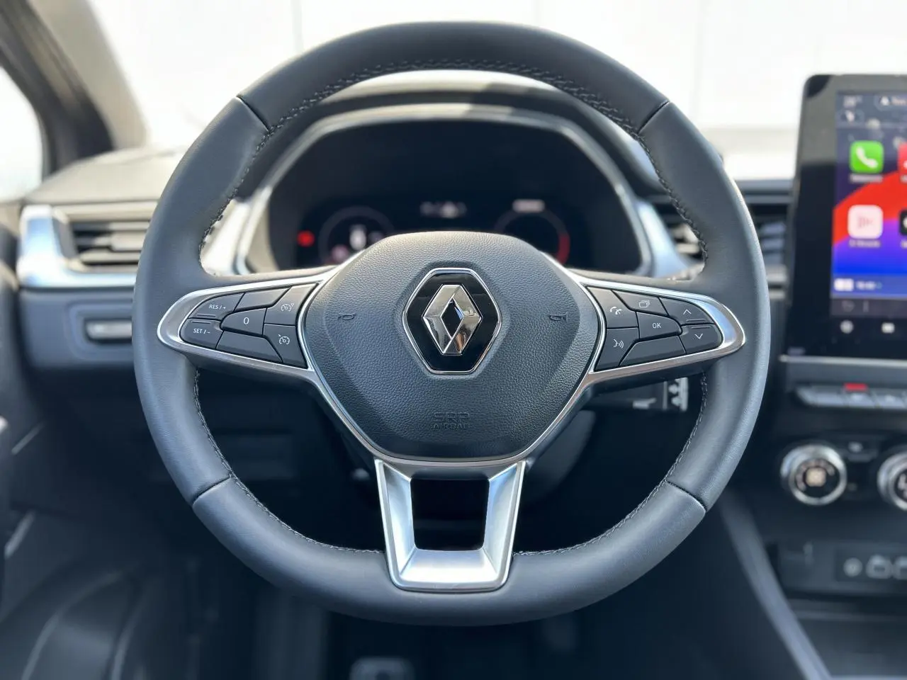 Volant cuir noir avec commandes intégrées, tableau de bord numérique et écran tactile du Renault Captur 2024.