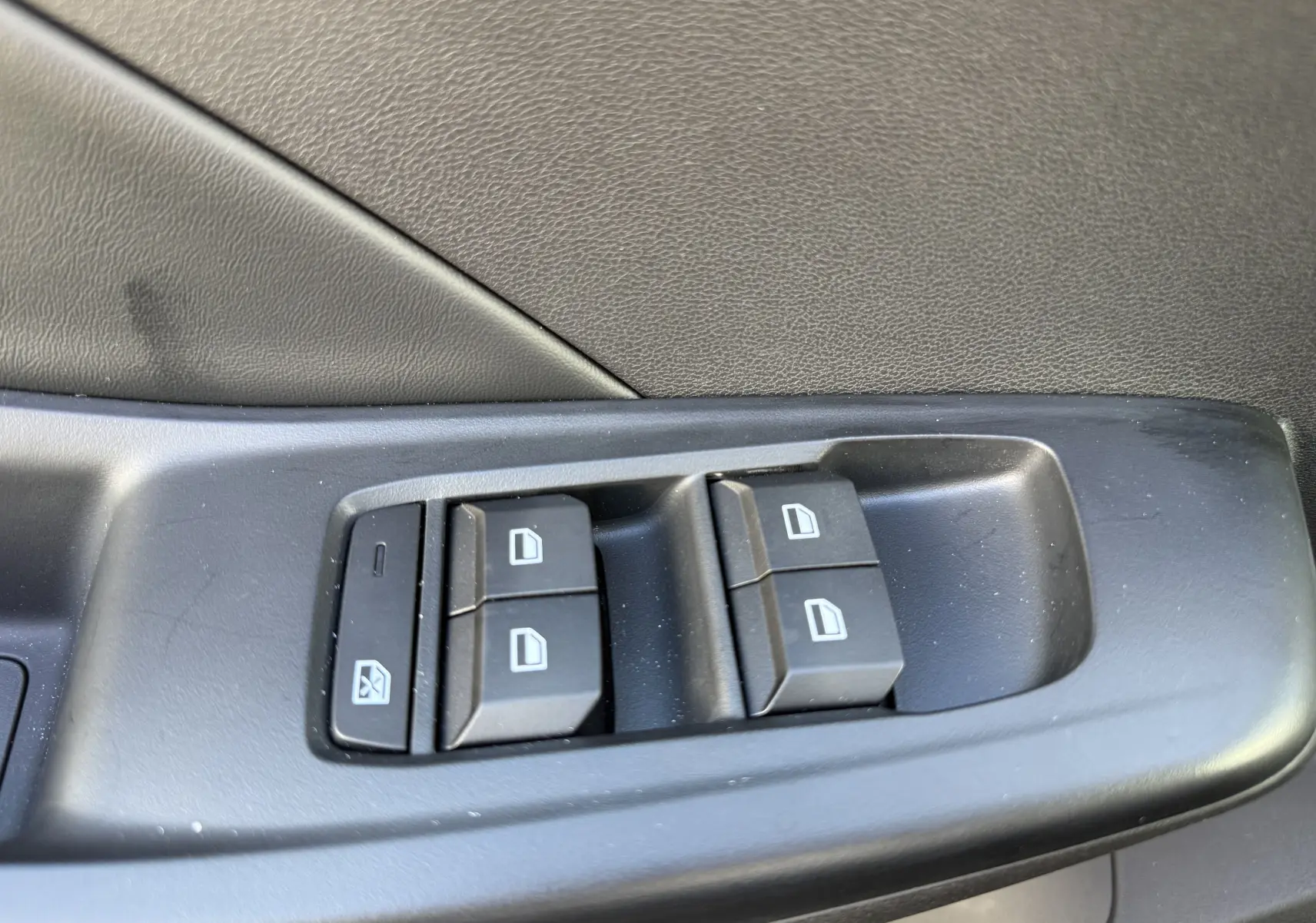 Gros plan sur les commandes de lève-vitres côté conducteur d’une MG3 1.5 HYBRID+ 195 LUXURY noir métal, intérieur noir.