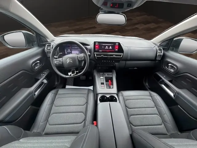 Vue intérieure avant du Citroën C5 Hybride gris clair 2024, tableau de bord avec écran tactile central et volant multifonctions cuir.