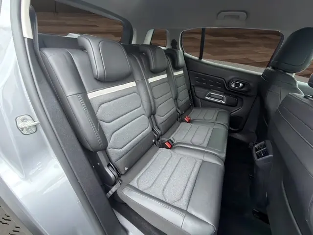 Vue intérieure côté droit des sièges arrière gris clair en tissu et cuir du Citroën C5 Hybride 2024, avec appuie-têtes et ceintures visibles.