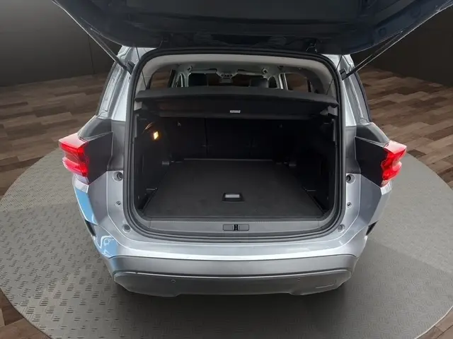 Vue arrière ouverte du coffre d'un Citroën C5 Hybride gris clair, montrant l'espace de chargement vide et l'éclairage intérieur.