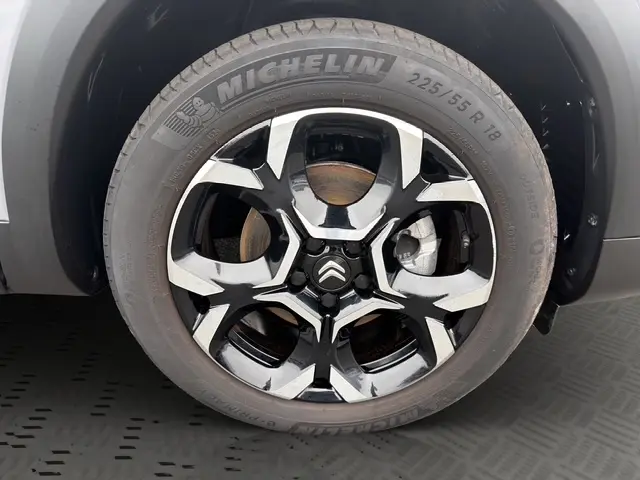 Gros plan sur la roue avant droite d'une Citroën C5 Hybride gris clair avec jante alliage bicolore et pneu Michelin.