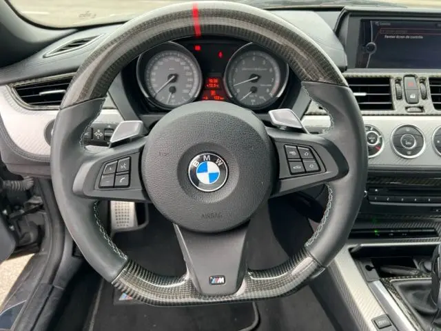 Volant sport en cuir et carbone avec logo BMW M, tableau de bord et console centrale du BMW Z4 Roadster gris 2012 vus de face.