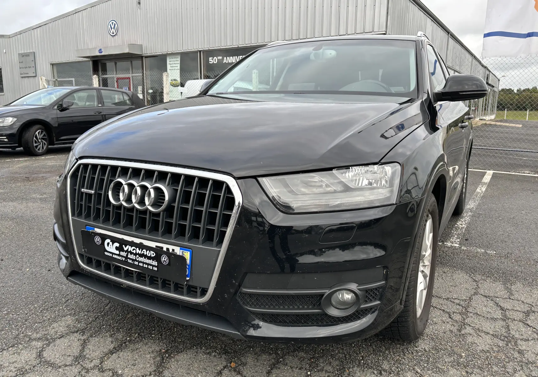 Audi Q3 noir vue 3/4 avant droit, mettant en valeur sa calandre distinctive et ses phares LED.