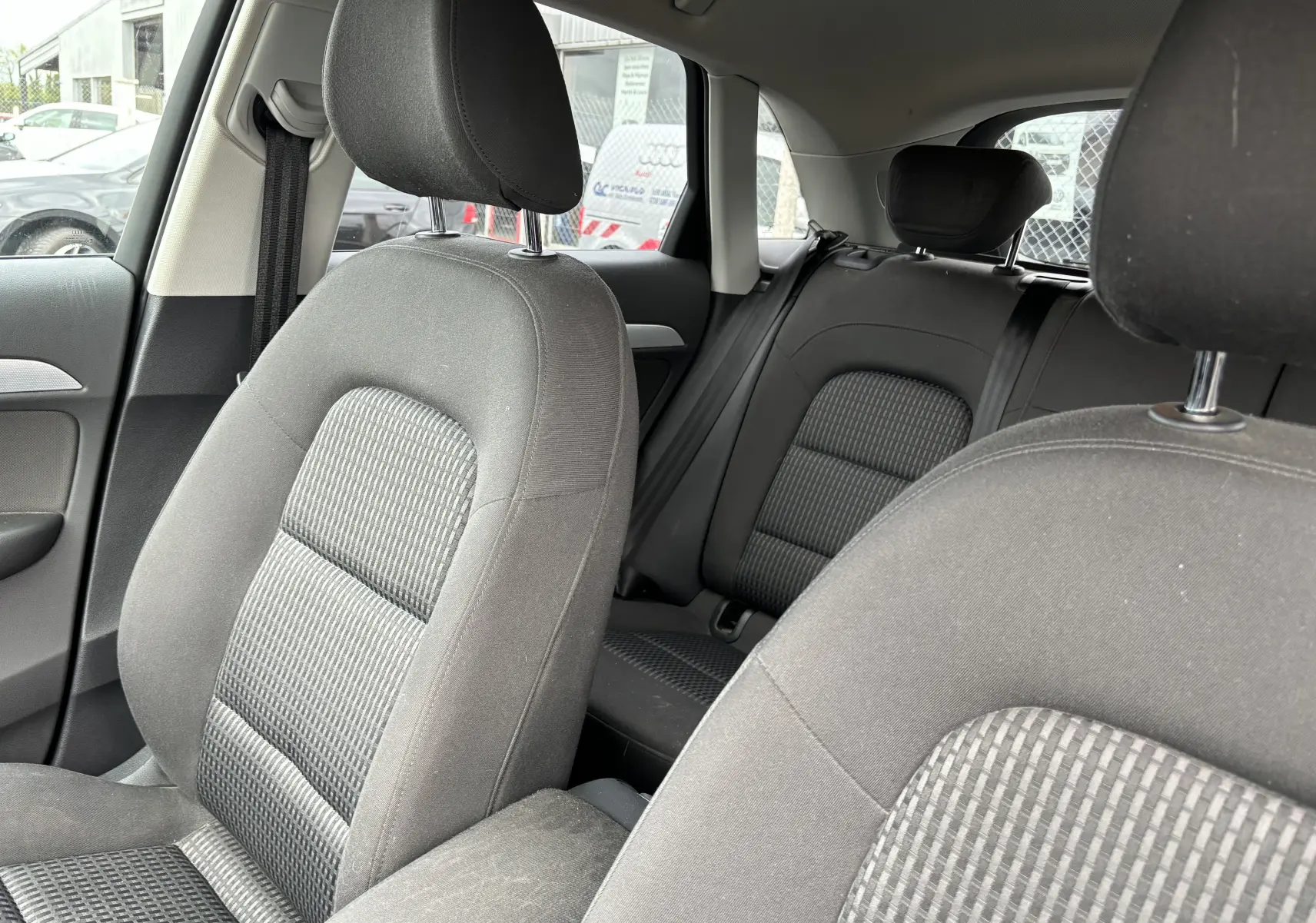 Intérieur noir de l'Audi Q3 2014, vue rapprochée des sièges avant et arrière en tissu avec appuie-têtes.