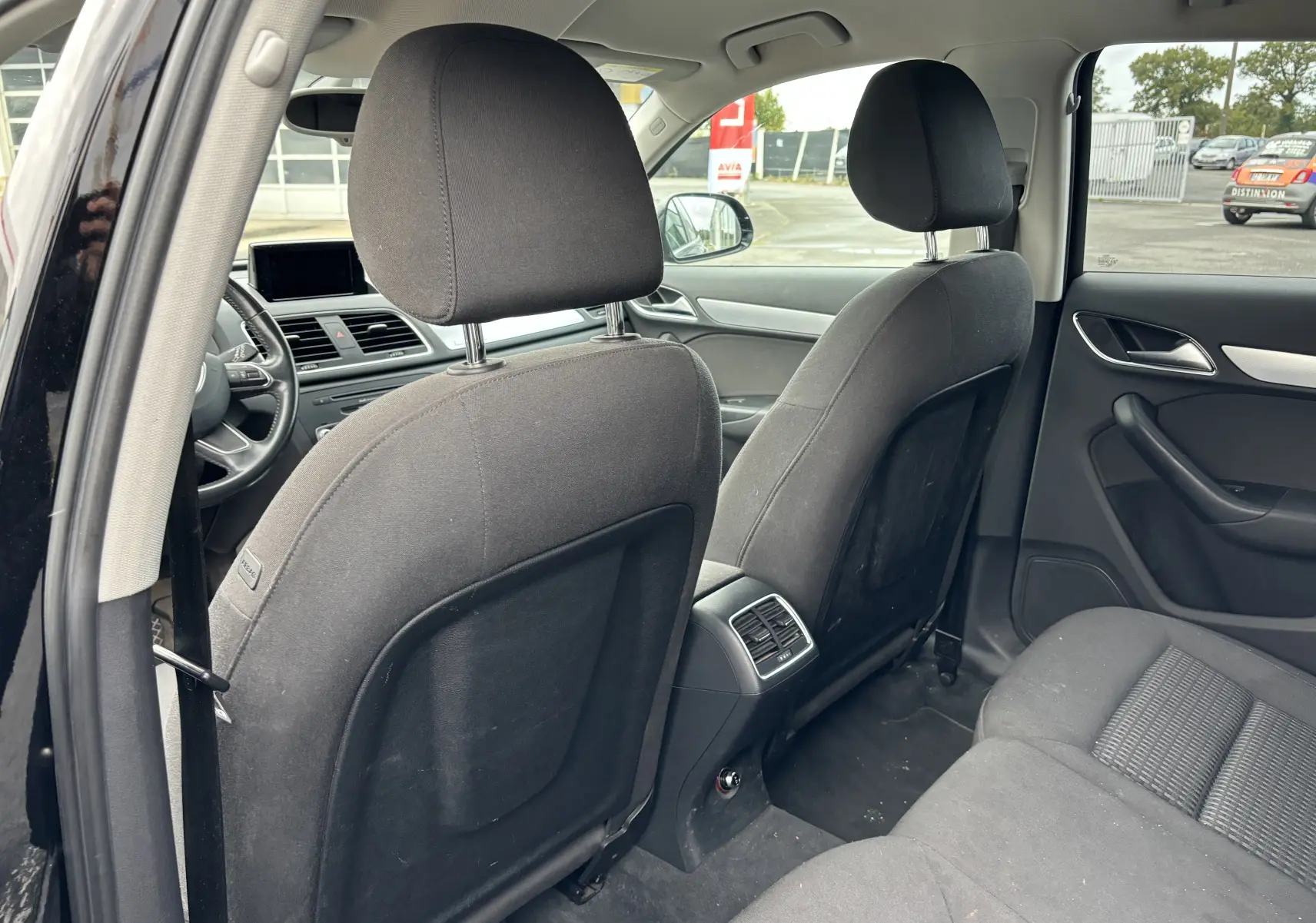 Vue arrière intérieure du Audi Q3 noir 2014 montrant les sièges avant et la banquette arrière en tissu noir.