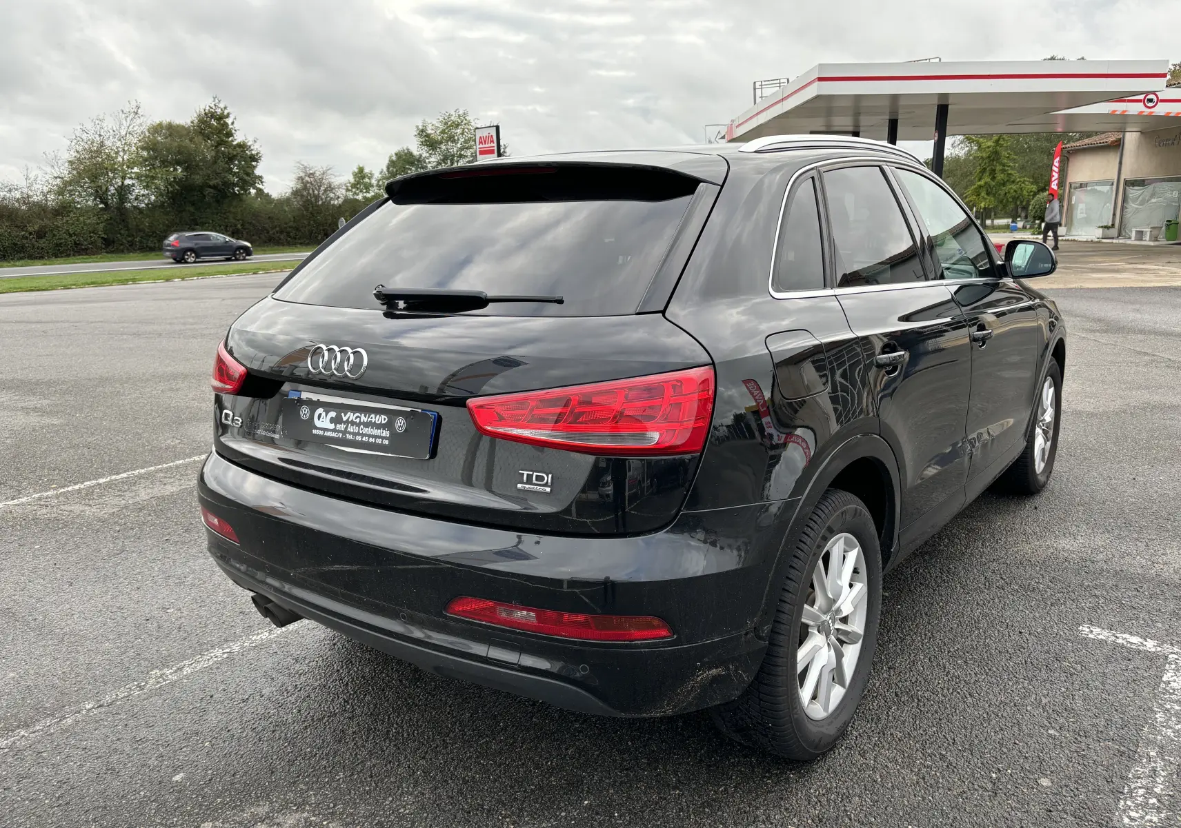 Audi Q3 noir vue 3/4 arrière droit stationné, avec feux arrière rouges et vitres teintées.