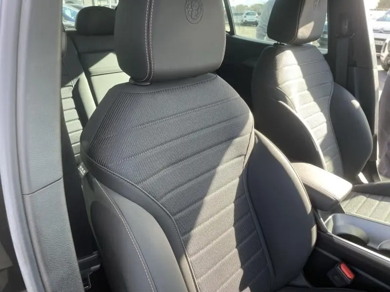 Vue rapprochée des sièges avant noirs de l'Alfa Romeo Tonale 2023 avec logo brodé sur les appuie-têtes.