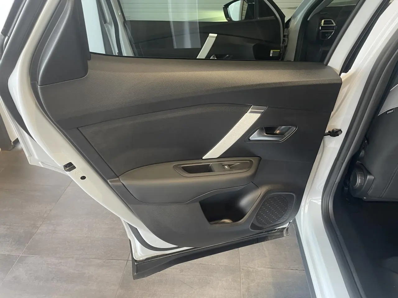 Vue intérieure de la porte arrière gauche d'une Citroën C4 blanche métallisée, avec garniture noire et insert argenté.