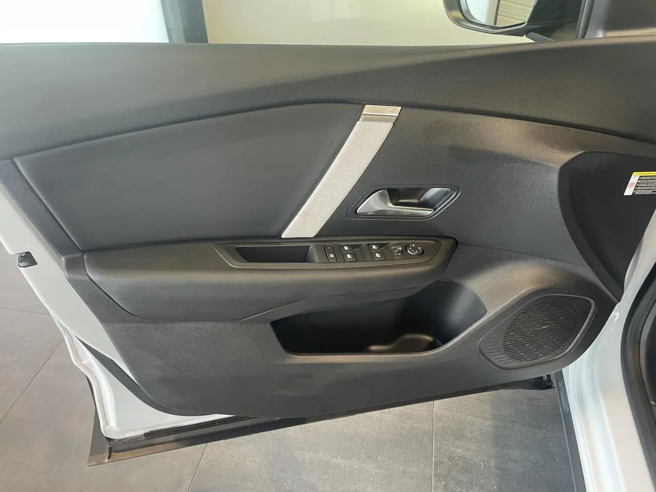 Porte avant gauche ouverte d'une Citroën C4 blanche métallisée, avec commandes de vitres et haut-parleur intégré.