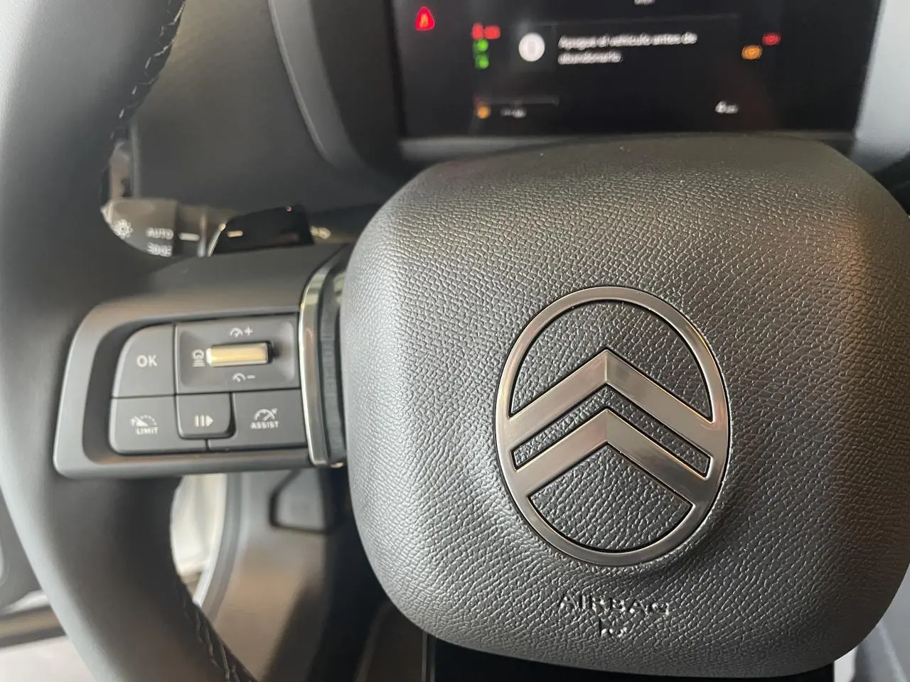 Gros plan sur le volant cuir noir de la Citroën C4 2025, avec commandes intégrées et logo chrome central.