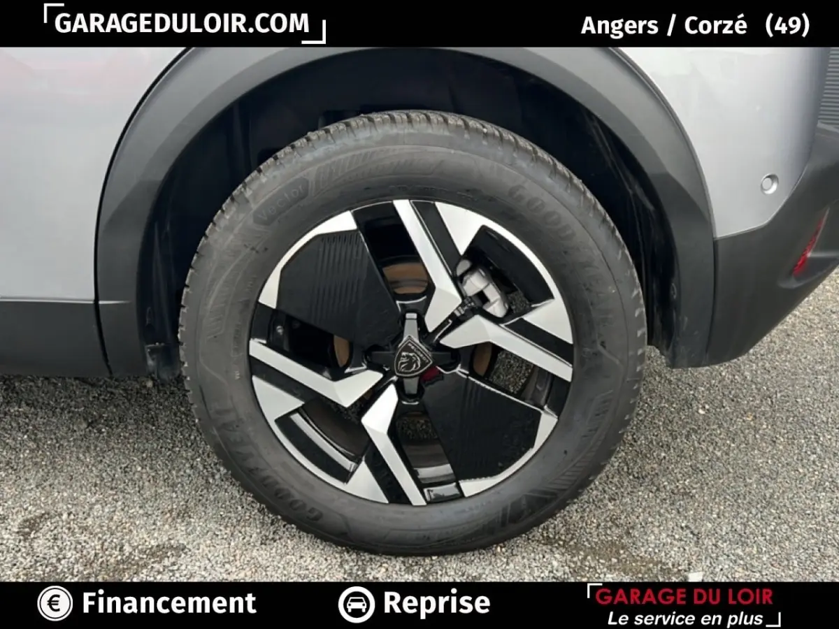 Gros plan sur la roue arrière droite d’un Peugeot 2008 Hybrid gris clair avec jante alliage noire et argentée.