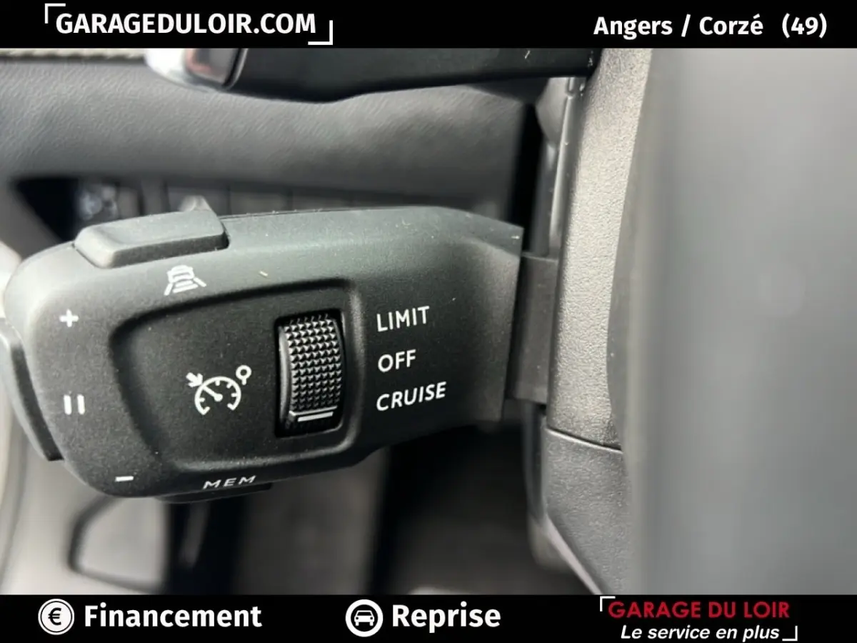 Gros plan sur la commande de régulateur de vitesse du Peugeot 2008 Hybrid gris clair, intérieur côté gauche.