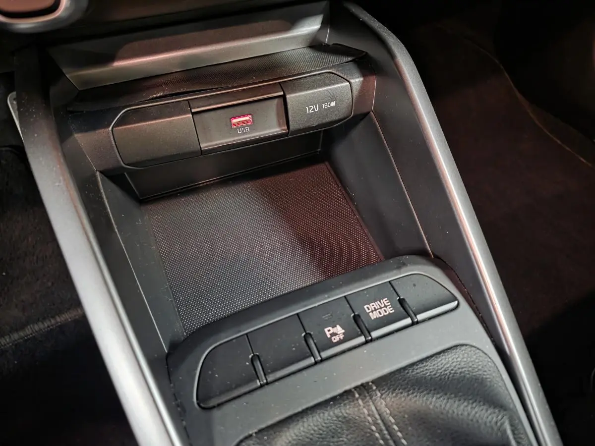 Gros plan sur la console centrale noire de la KIA RIO GT Line 2022, avec ports USB et bouton Drive Mode.