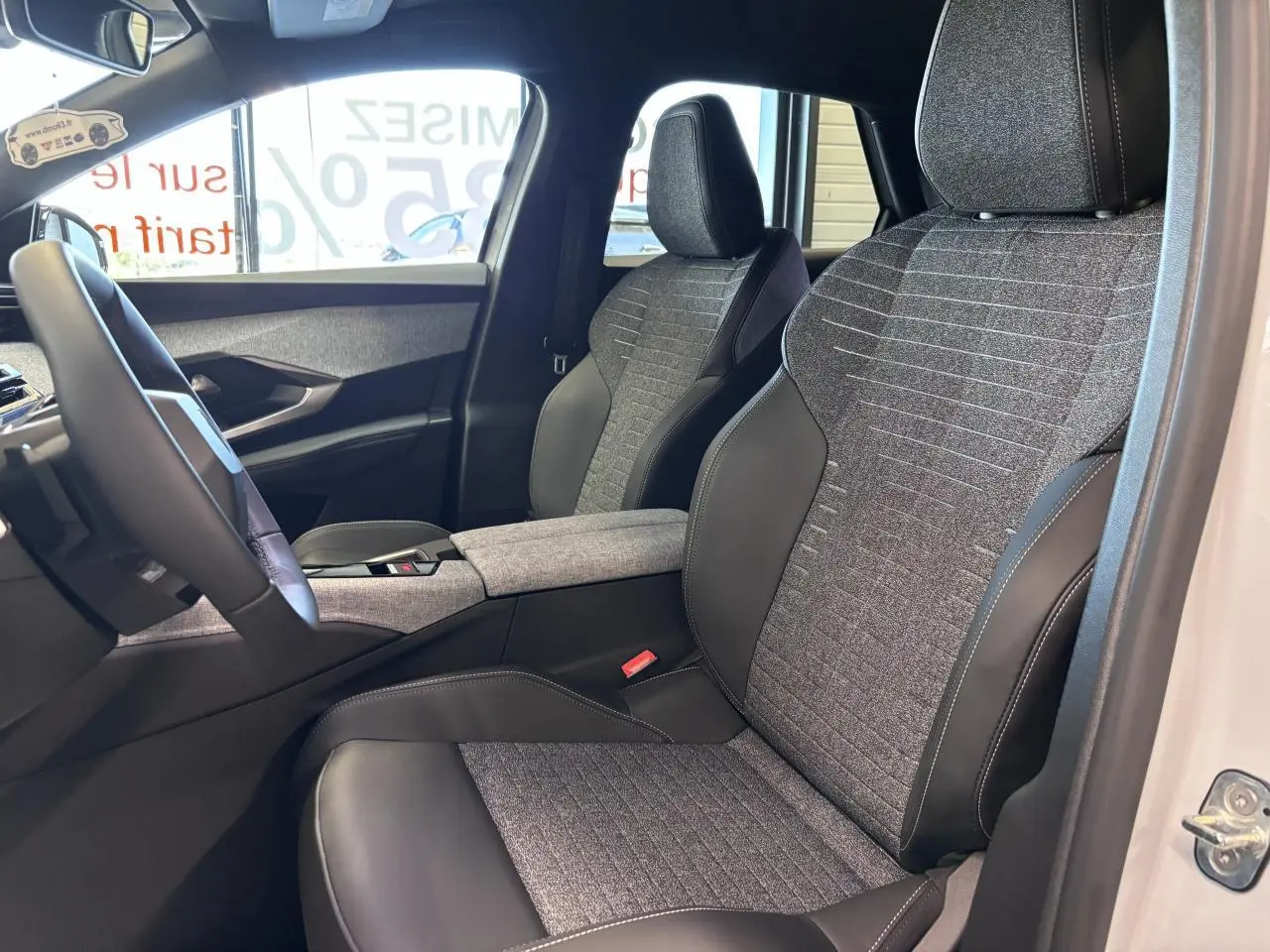 Vue intérieure côté gauche du Peugeot 3008 blanc 2026, sièges tissu gris et cuir noir avec accoudoir central.