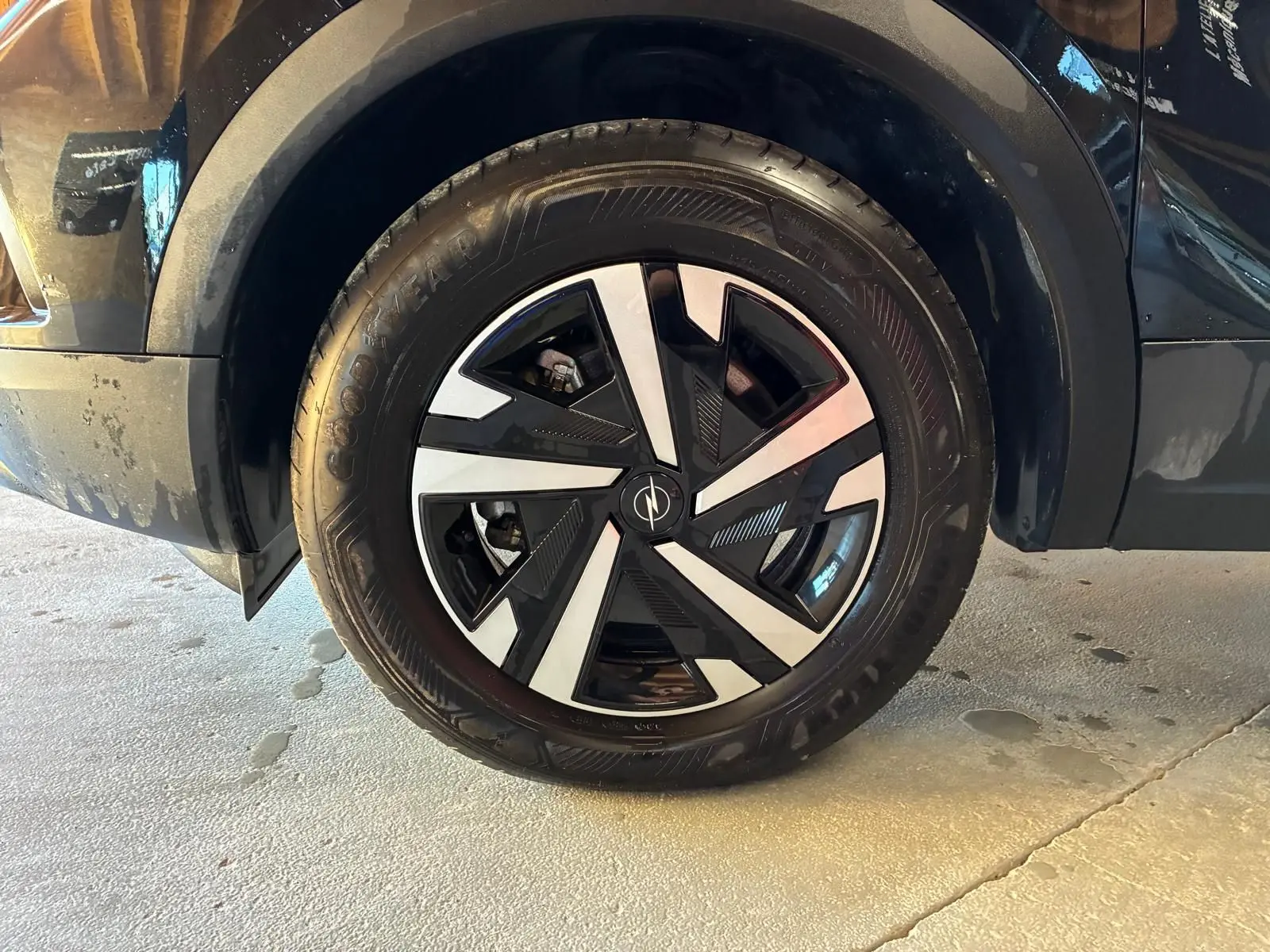 Gros plan sur la roue avant gauche noire d'un Opel Mokka 2025, jante alliage au design géométrique bicolore.