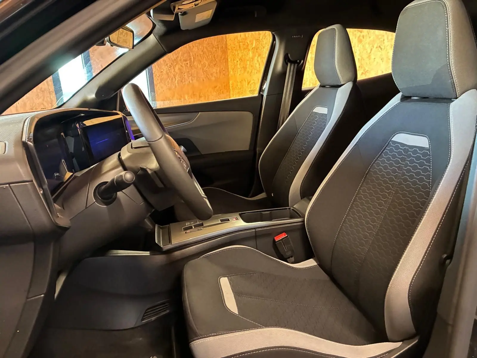 Vue intérieure côté conducteur de l’Opel Mokka 1.2 Turbo 145 Edition 2025, sièges tissu noir avec surpiqûres grises.