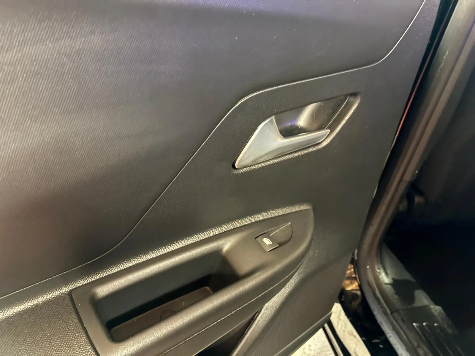 Gros plan sur la porte arrière droite noire de l'Opel Mokka 2025, montrant la poignée intérieure et le bouton de verrouillage.