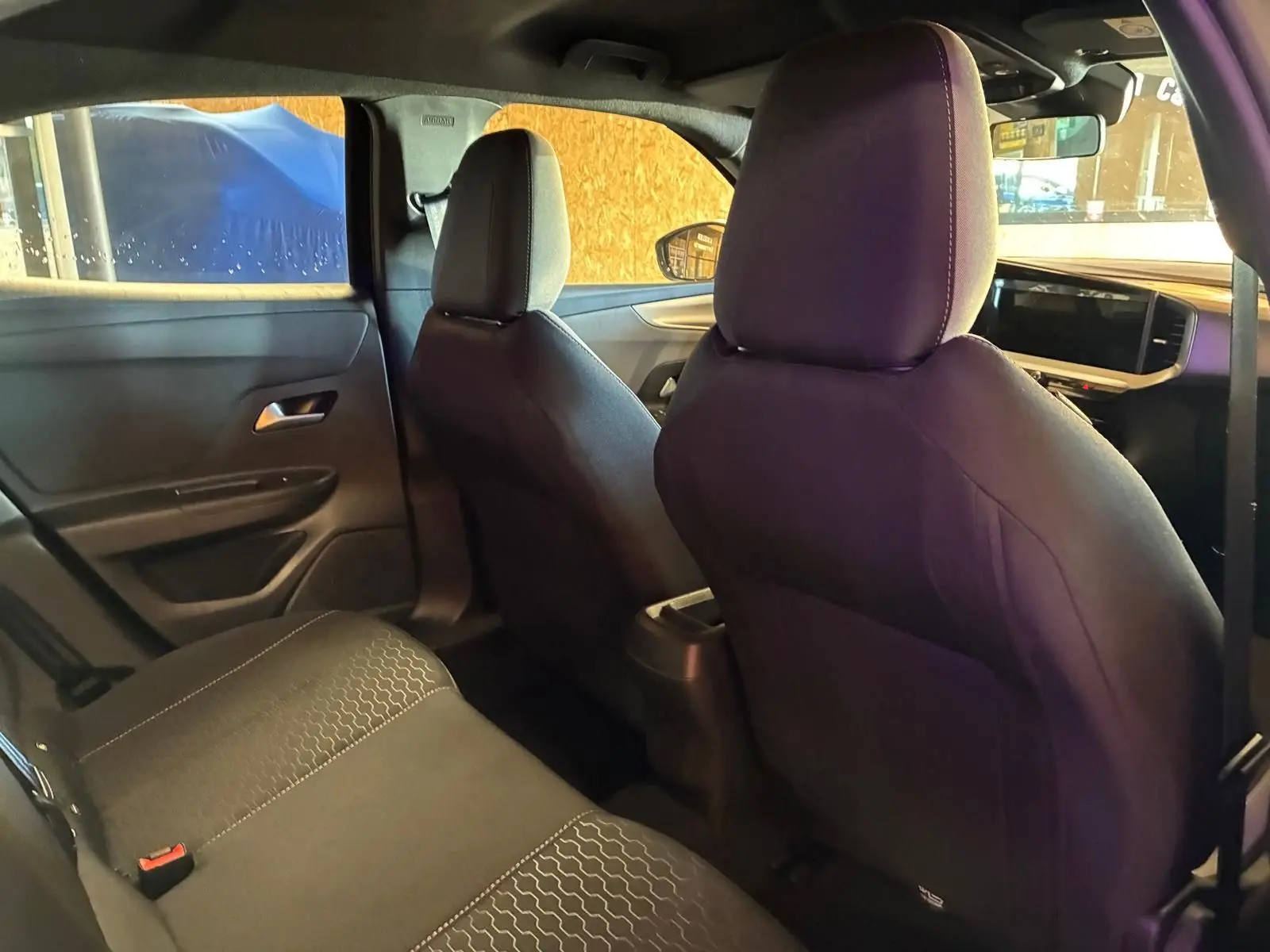 Vue intérieure arrière droite de l’Opel Mokka 2025 noir, sièges tissu noir avec coutures claires et tableau de bord moderne.
