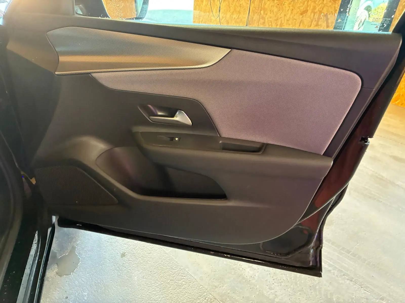 Vue intérieure de la porte côté gauche de l’Opel Mokka noir 2025, avec garniture tissu et plastique noir.