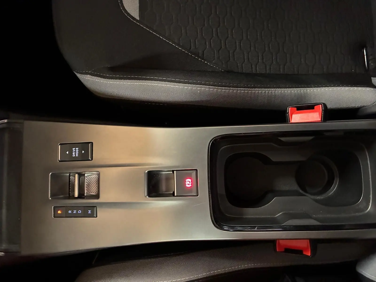 Vue plongeante sur la console centrale noire de l'Opel Mokka 2025, avec levier de boîte auto et bouton frein à main électrique allumé.