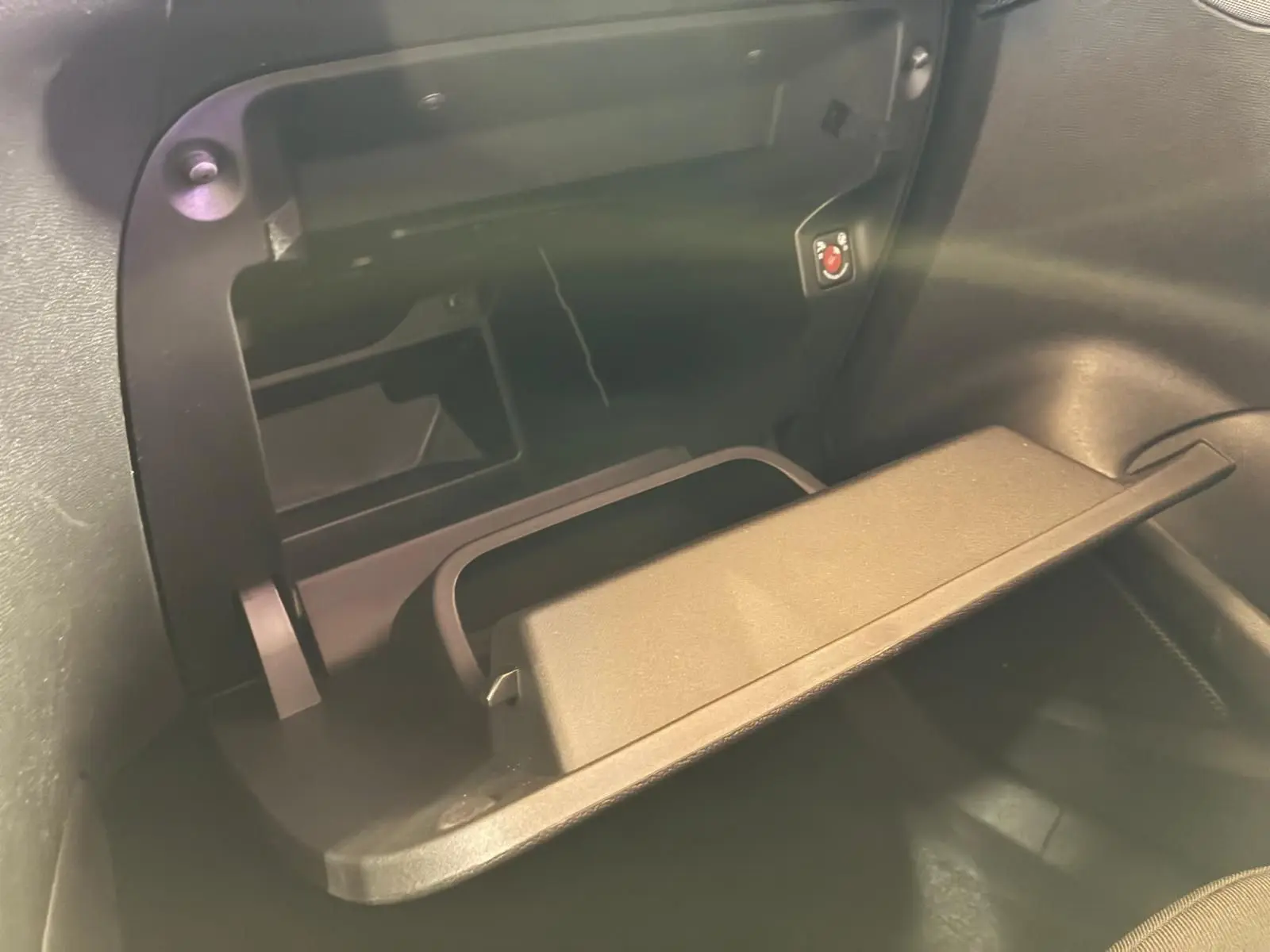 Gros plan sur la boîte à gants ouverte de l’Opel Mokka 1.2 Turbo 145 Edition noire, montrant son espace de rangement intérieur.