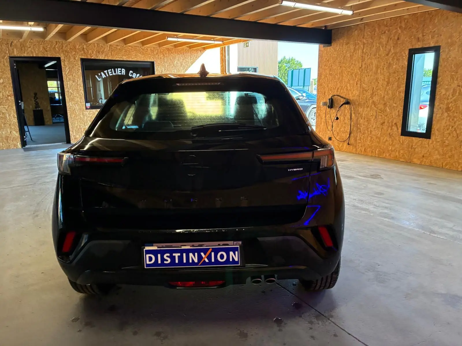 Vue arrière d'un Opel Mokka 1.2 Turbo 145 Edition noir hybride stationné dans un garage lumineux.