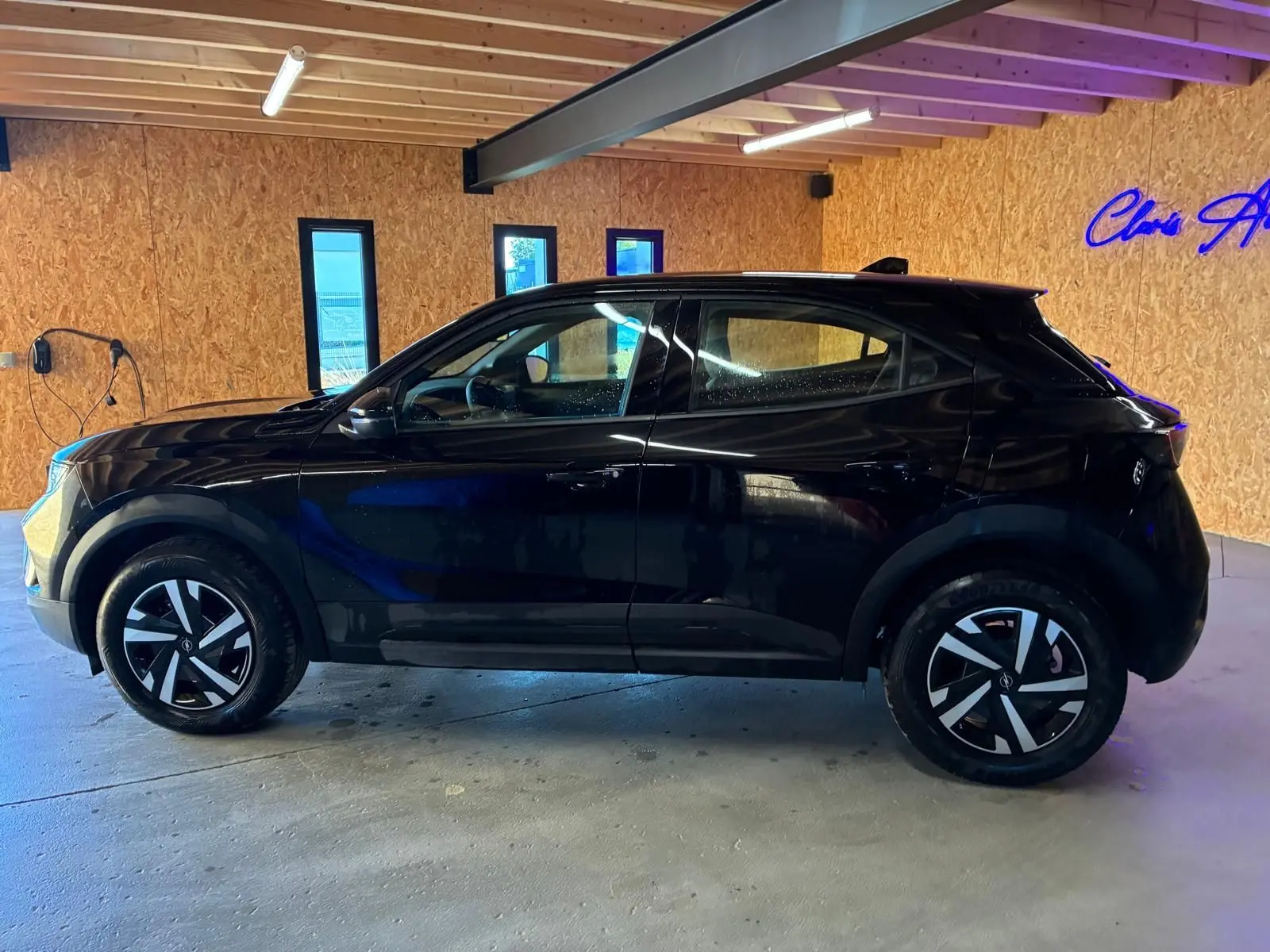 Vue latérale gauche d’un Opel Mokka 1.2 Turbo 145 Edition noir brillant, avec jantes distinctives et toit noir en intérieur bois.
