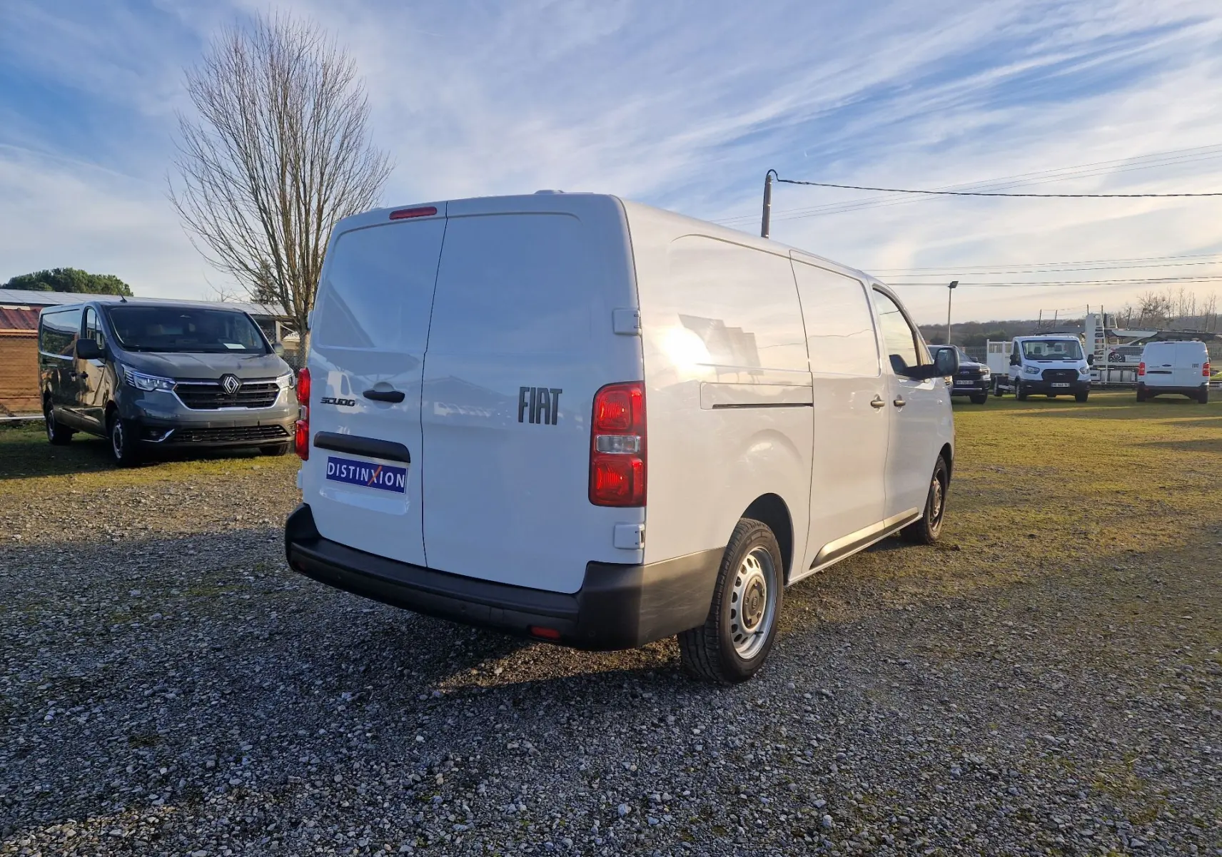 Vue 3/4 arrière droite d’un FIAT Scudo Fourgon blanc 2024 avec hayon arrière fermé sur un terrain extérieur.