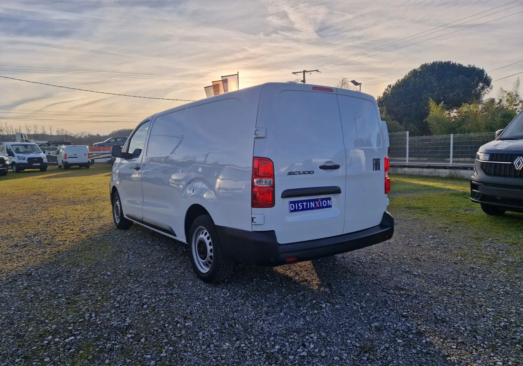 Vue 3/4 arrière droite d’un FIAT Scudo fourgon blanc 2024 avec plaque de protection et pare-chocs noirs sur un terrain extérieur.