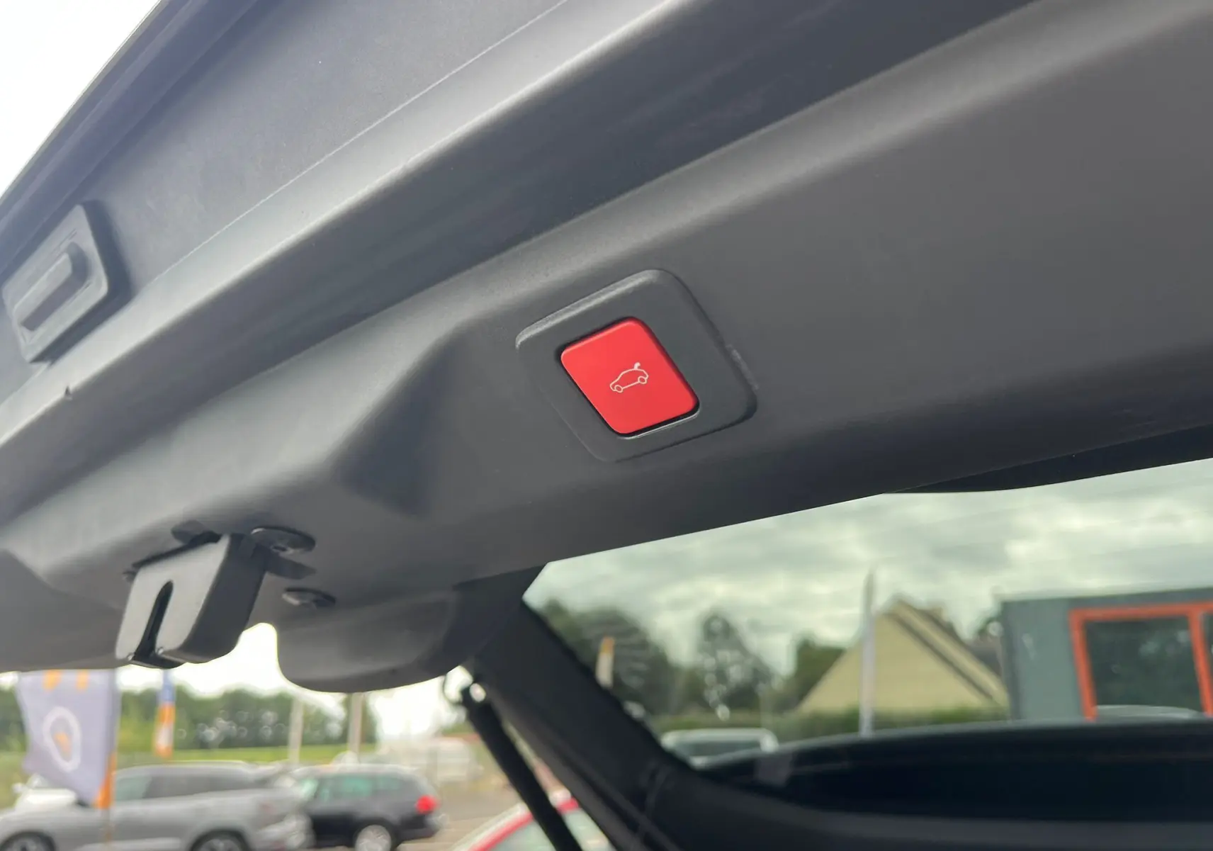Bouton rouge d'ouverture électrique du hayon sur le coffre arrière du Peugeot 3008 gris titane 2025.