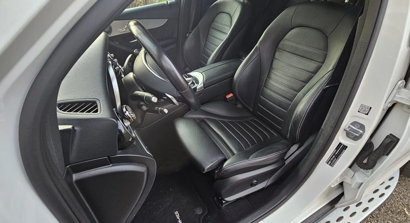 Intérieur côté conducteur du Mercedes GLC 220 Coupé blanc 2018, sièges cuir noir et tableau de bord visible.