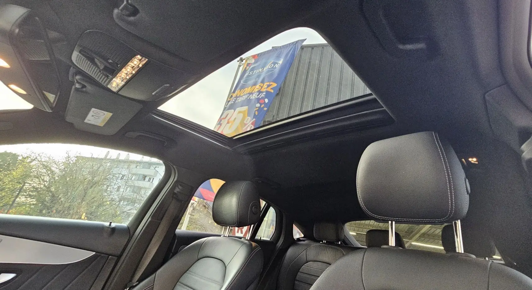 Intérieur noir d'une Mercedes GLC 220 Coupé 2018 avec toit ouvrant panoramique et sièges en cuir visibles côté gauche.