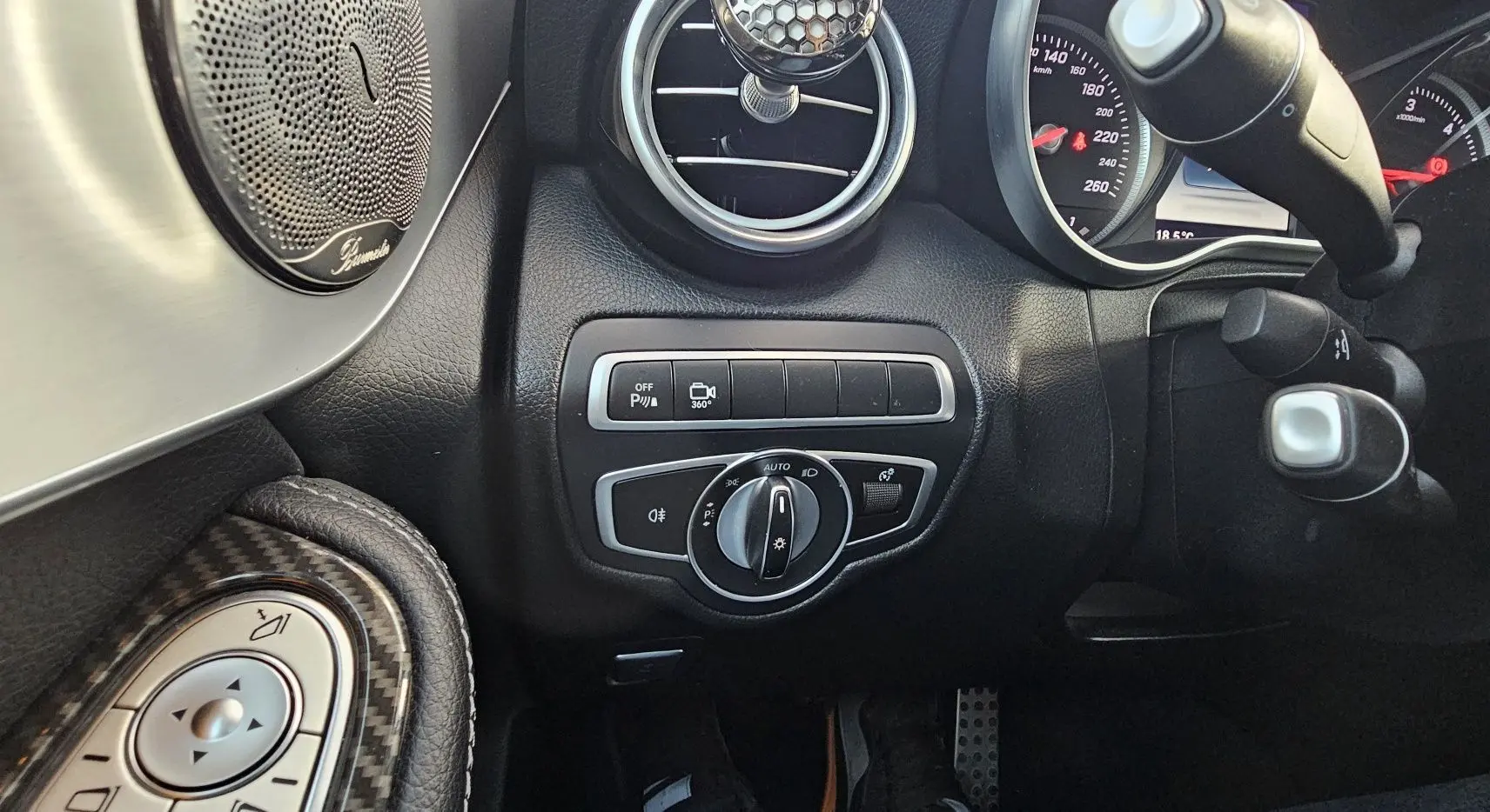 Vue rapprochée du tableau de bord côté gauche du Mercedes GLC 220 Coupé blanc, avec commandes d’éclairage et haut-parleur Burmester.