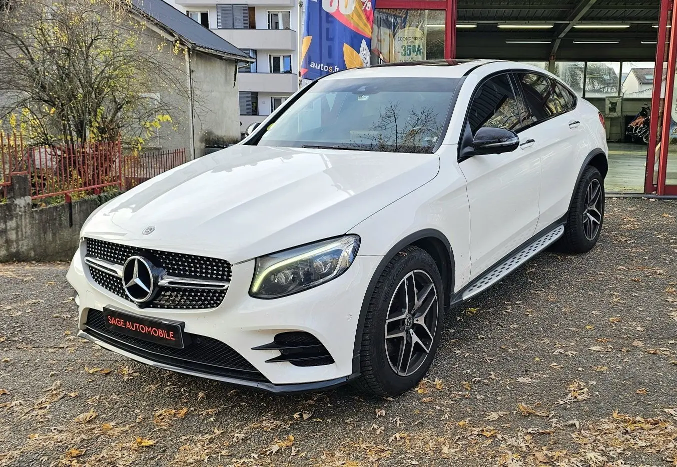 Vue 3/4 avant d'un Mercedes GLC 220 Coupé blanc avec jantes noires et calandre étoilée brillante.