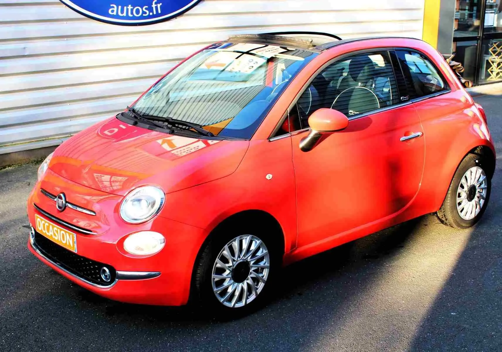 Vue arrière d'une FIAT 500C 2018 Pastel Coral Red avec capote ouverte et plaque "OCCASION" visible.