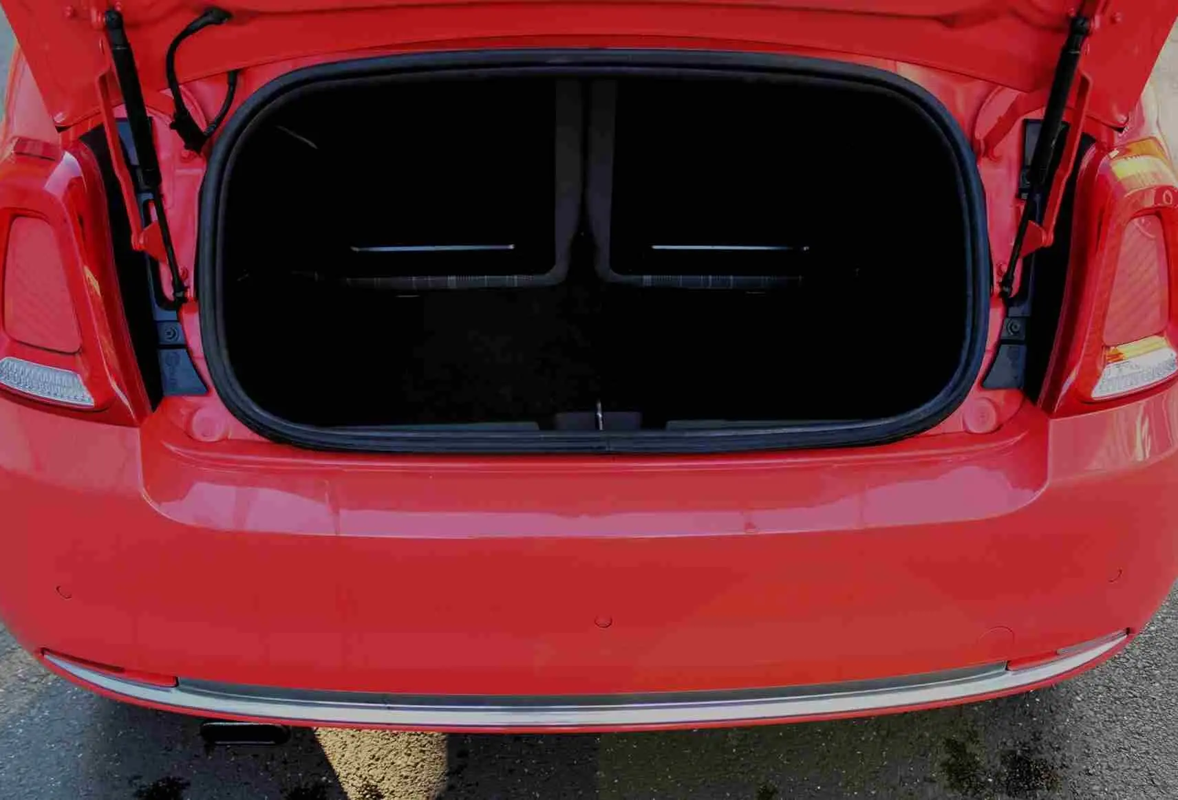 Gros plan sur la roue avant gauche d'une FIAT 500C rouge Pastel Coral avec jante argentée à rayons fins.